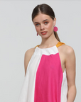 Model wearing bright pink Grian leather earrings with circular shape and gold hooks, styled with a pink and white dress against a grey background