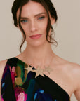Model wearing the Réalt Star Necklace in gold leather, styled with a one-shoulder floral dress for a statement look