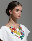 Model wearing a statement star necklace in multicoloured Italian leather with layered stars on gold chain, styled with a white top