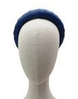 Navy blue padded satin headband displayed on a neutral-toned mannequin head against a white background