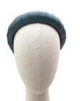 Deep teal padded satin headband displayed on a neutral mannequin head against a white background