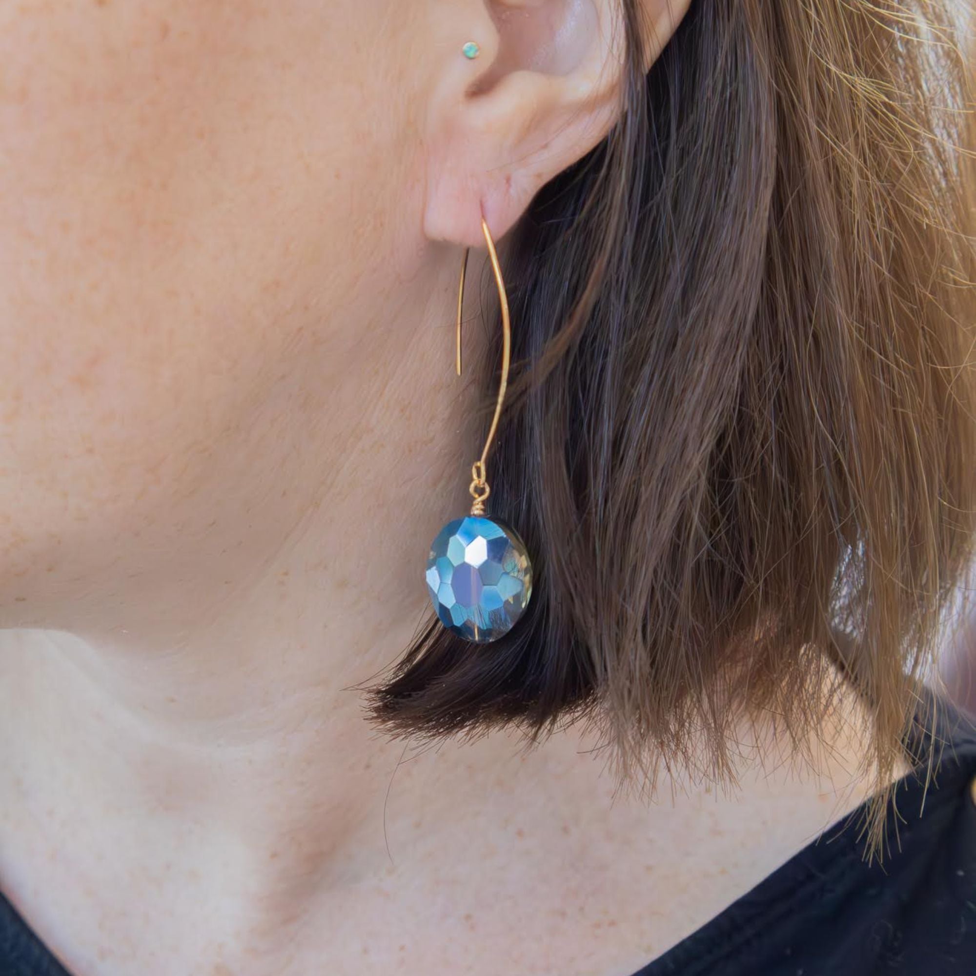Large oval earrings catching rainbow colours on model