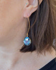 Large oval earrings catching rainbow colours on model