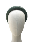 Dark green satin-look padded headband displayed on a neutral mannequin head against a white background