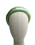 Metallic green satin-look padded headband on a neutral mannequin head with white background